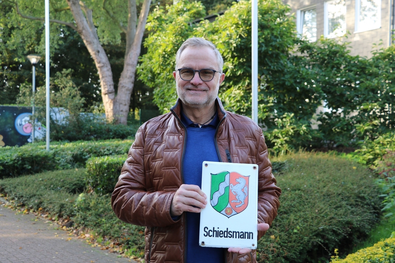 Jörg Middelhoff hält das Schild des Schiedsmannes.