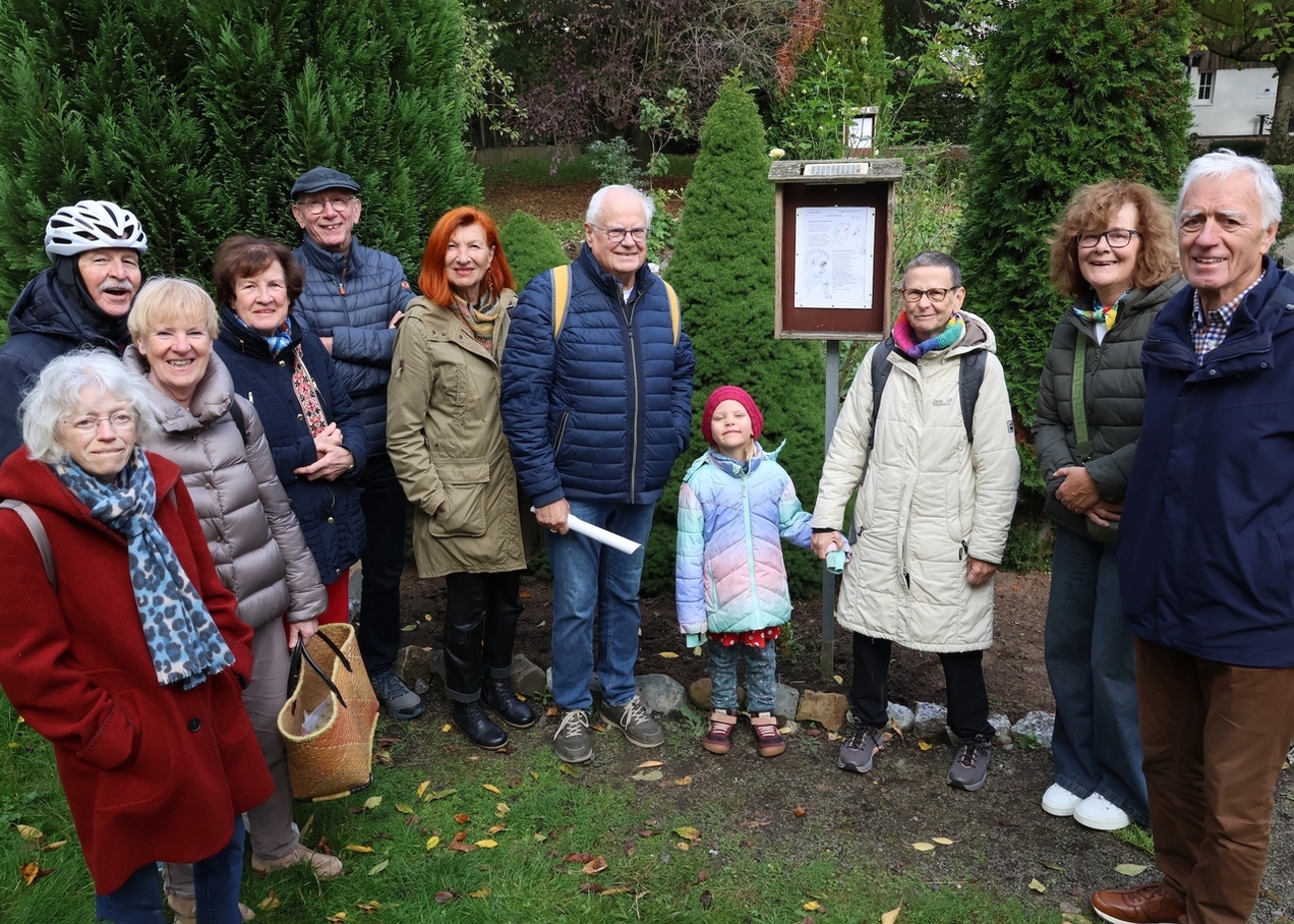 Die Initiatoren des Lyrikpfads und einige Lyrikfreunde stehen im Bauerngarten vor der Gedichtstaffel am Hof Jünger.