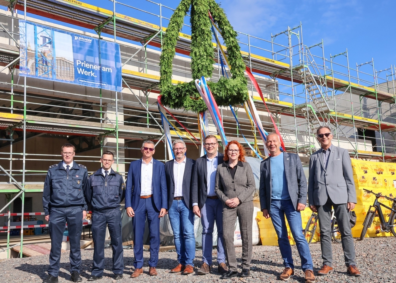 Vertreter der Feuerwehr, Politik und Stadtverwaltung stehen unter dem Richtkranz an der Feuerwache in Kirchhellen.