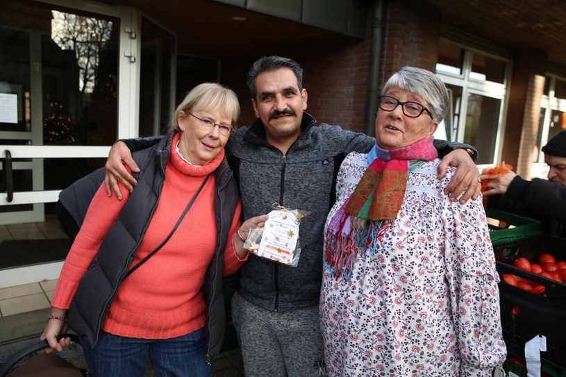 Die Helferinnen Birgit Schulz und Christiane Wilkin verteilen Essensgutscheine an Familien wie die von Mohammed, der sich sichtlich über diese Geste freut.