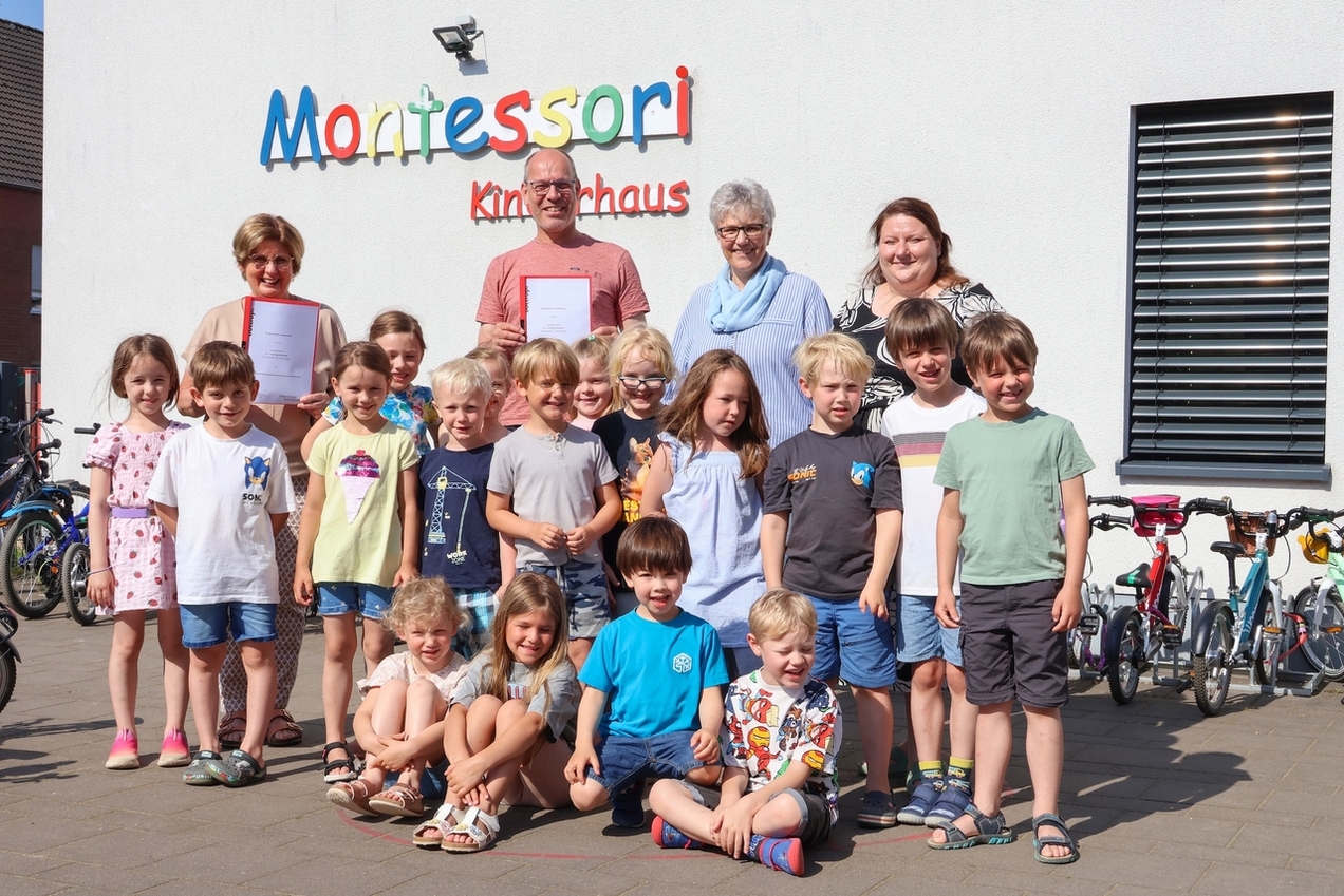 Die Kinder des Montessori Kinderhauses am Tappenhof freuen sich gemeinsam mit der Einrichtungs- und Bibliotheksleitung über die Kooperationsvereinbarung.