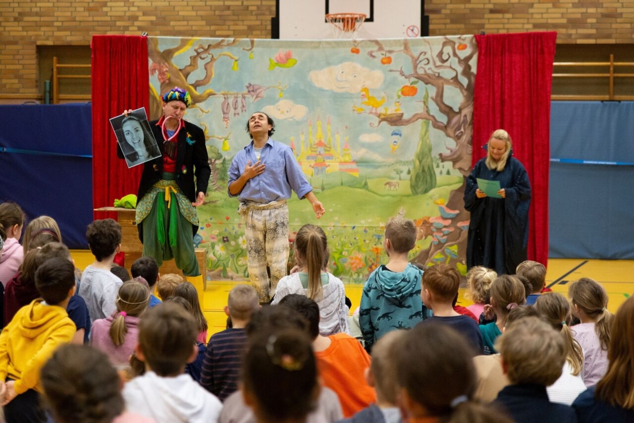 Papageno und Prinz Tamino stehen gemeinsam mit Lehrerin Alexandra Notthoff als die Königin der Nacht auf der Bühne in der Turnhalle.