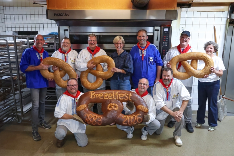 Die Brezelmajestäten gemeinsam mit den Brezelbäckern und dem Riesenbrezel in Markus Kläseners Backstube.
